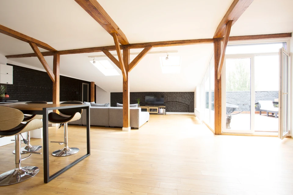 Espace de vie moderne avec cuisine ouverte et salon sous charpente apparente en bois