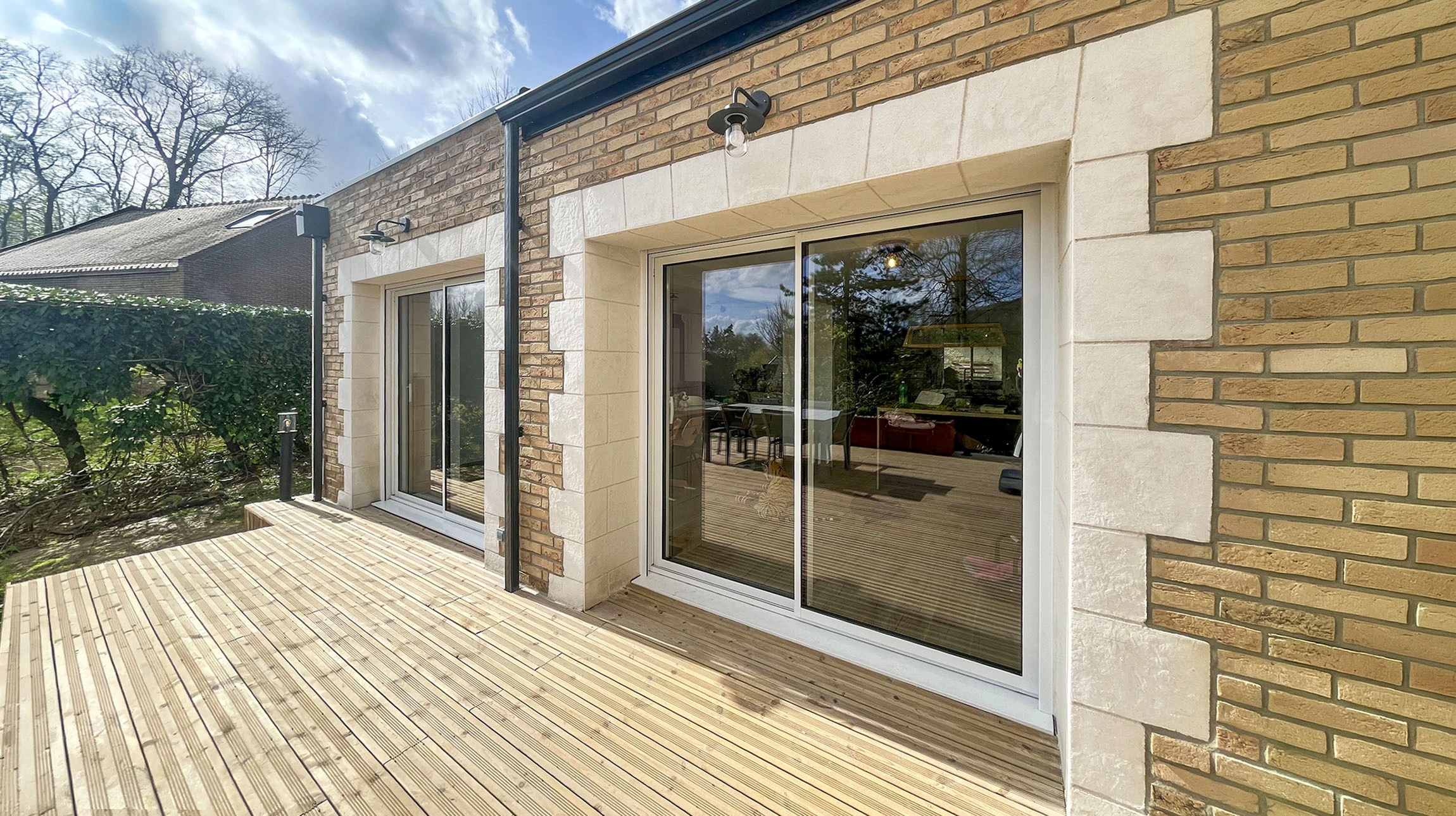 Fa&ccedil;ade moderne de maison contemporaine avec mur-rideau vitr&eacute; triangulaire et ma&ccedil;onnerie de briques apparentes