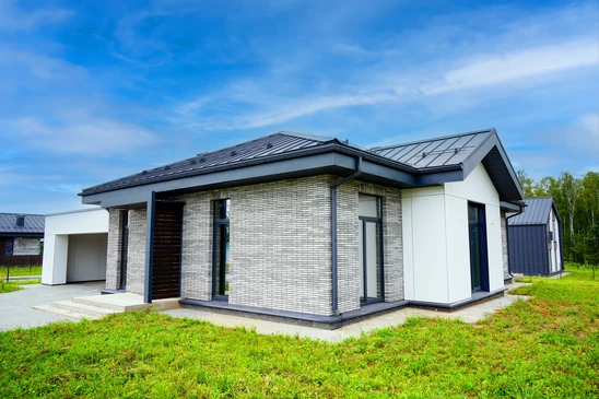 Chantier de construction ext&eacute;rieur montrant une toiture en cours de r&eacute;alisation sur maison en parpaings gris