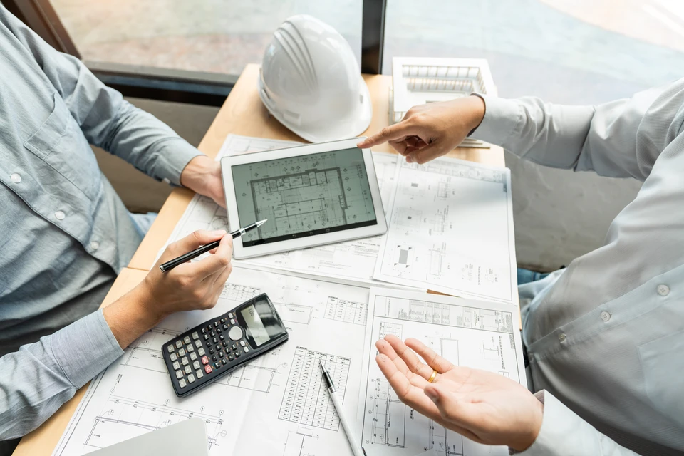 Réunion d'affaires en intérieur avec trois professionnels en costumes consultant un ordinateur portable