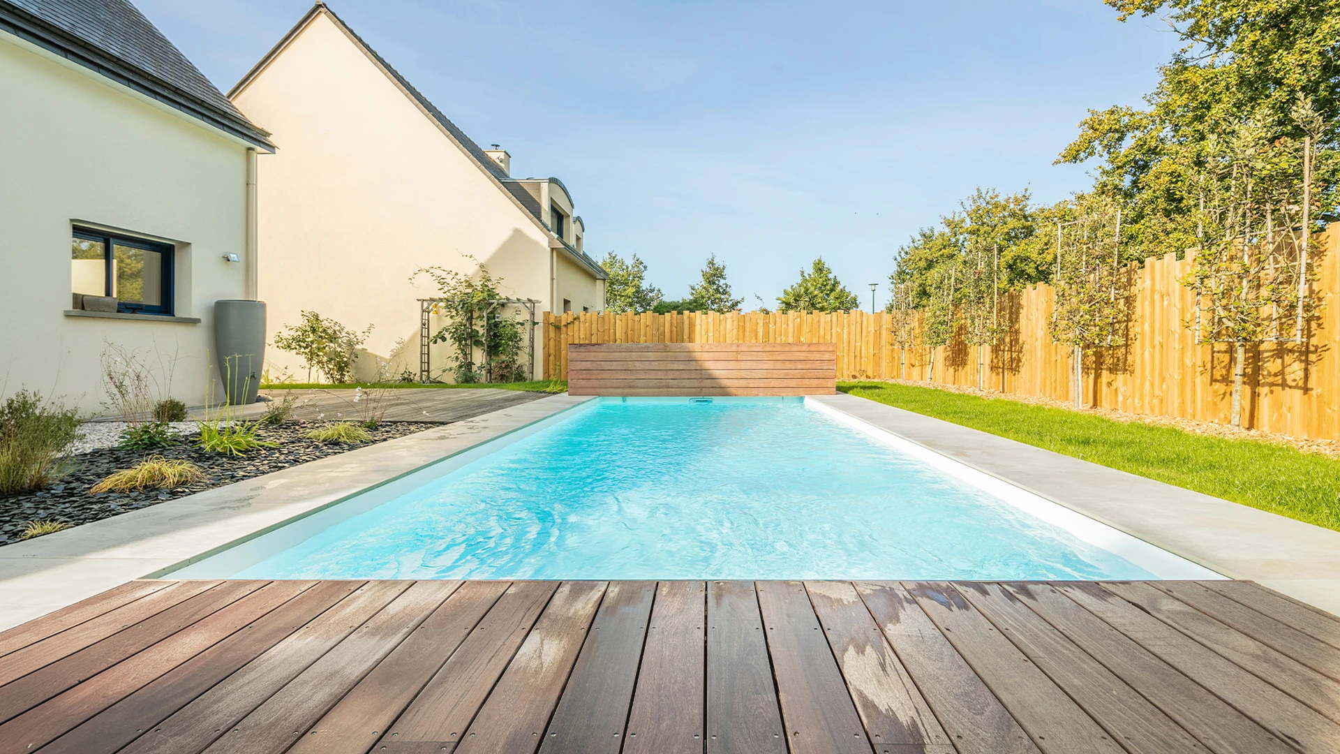Vue aérienne d'une piscine rectangulaire avec eau turquoise cristalline et plage en bois exotique