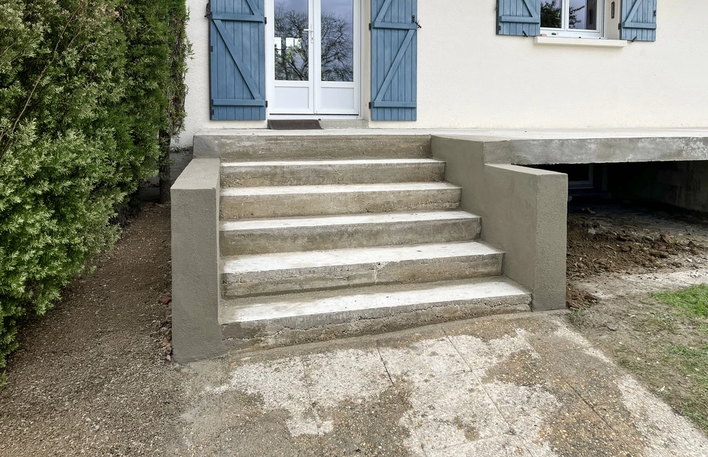 Chantier extérieur résidentiel avec allée en gravier fraîchement posée longeant une clôture grillagée